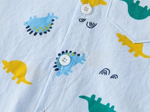 Gros plan détaillé sur une chemise enfant bleu clair avec motifs de dinosaures