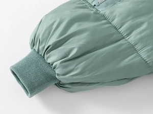 Detailed view of the sage green kids winter coat with ribbed cuffs and smooth zipper