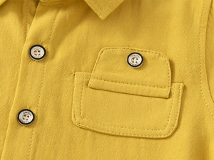 Macro detail of ginger yellow cotton shirt featuring chest pocket and classic buttons