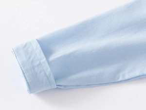 Detailed close-up of light blue long-sleeved shirt cuff with neat stitching