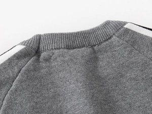Détail d'un pull gris pour garçon avec rayures contrastées blanches sur l'épaule et col rond