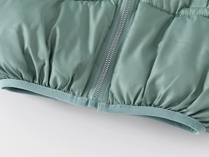 Detail of the high-quality resin zipper and elastic hem on the green quilted winter coat