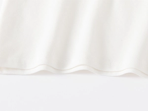 Close-up of piqué cotton fabric and double-needle hem on a white polo shirt for kids