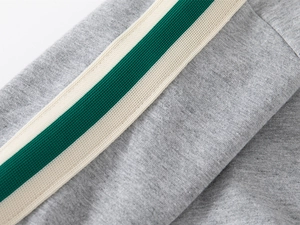 Detail of grey knitted fabric featuring green and white striped ribbon trim on sleeve