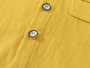 Macro detail of yellow cotton shirt featuring a classic engraved button and fine stitching