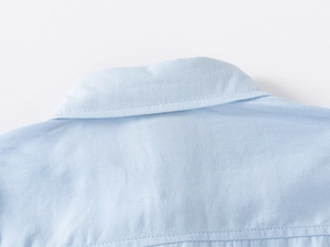 Macro detail of sky blue boys shirt collar showing premium twill fabric texture