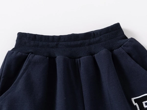 Detail of navy knit joggers showing elastic ribbed waistband and R letter embroidery