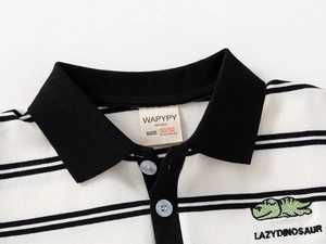 Detail of baby polo shirt collar with dinosaur embroidery and black striped fabric