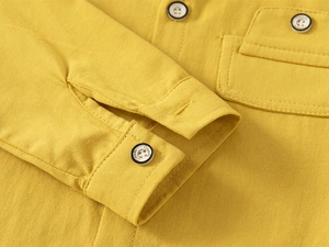Detail of yellow cotton shirt featuring a flap chest pocket and classic white buttons