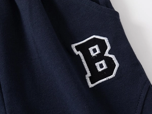 Detailed close-up of premium navy blue fabric with white embroidered letter B patch