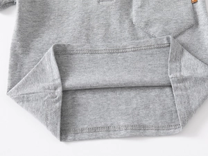 Detailed macro view of gray knitted polo shirt with chest pocket and orange logo tag
