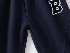 Detail of navy blue knit joggers featuring a high-quality letter B patch embroidery