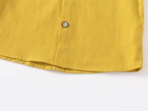 Close-up of yellow cotton shirt hem with double stitching and classic button detail