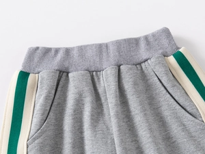 Detail of gray kids' joggers featuring elastic ribbed waistband and side stripe accents