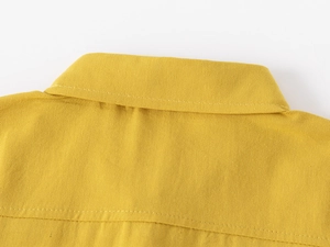 Detail view of bright yellow cotton shirt collar and shoulder stitching on white background