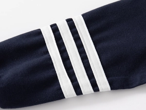Detailed macro view of navy blue knit sweatshirt sleeve with triple white stripes