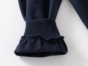 Detail of navy cotton jogger pants showing ribbed cuffs and ruffled hem stitching