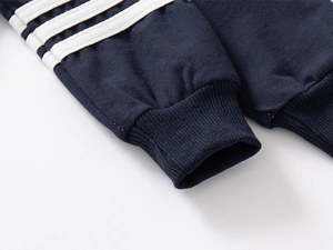 Close-up of navy blue knit sweatshirt sleeve with ribbed cuff and white triple stripes