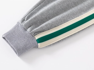 Detail of grey knit fabric texture with green and white striped side ribbon and ribbed cuff