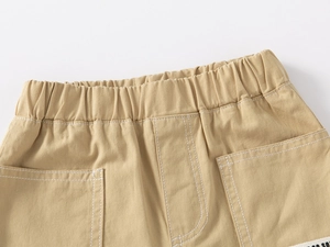 Detail of boys khaki shorts showing elastic waistband and large pocket with white stitching