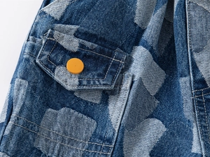Detail of denim shorts with orange button, flap pocket and heart-shaped wash texture