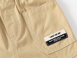 Close-up of khaki cotton cargo shorts pocket with contrast stitching and woven label