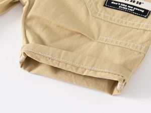 Detailed close-up of khaki cotton twill fabric with contrast stitching and woven label