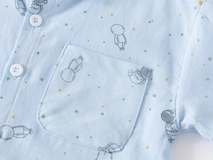 Detail of baby boys light blue short sleeve shirt with astronaut print and chest pocket