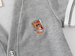 Detail of grey knitted cardigan with cartoon bear embroidery and white sleeve stripes