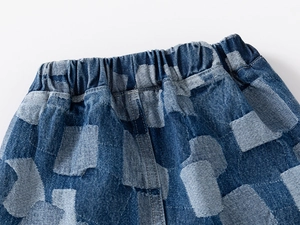 Close-up of boys' denim shorts featuring elastic waist and blue patchwork pattern