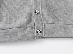Macro view of grey knitted cardigan texture with two silver metallic buttons and neat stitching
