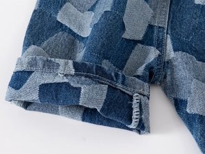 Detailed macro view of children's denim shorts showing blue patchwork pattern and hem stitching
