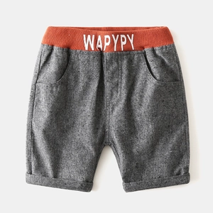 Detail of boys' grey knit shorts with orange elastic waistband and WAPYPY text print