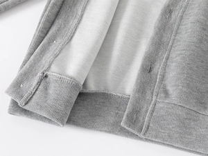 Detailed close-up of ribbed hem and inner lining on grey knitted toddler cardigan jacket