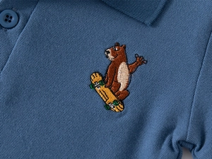 Vue détaillée du polo bleu marine pour enfants avec broderie ours de qualité sur coton