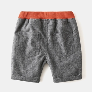 Detail of boys' dark grey knit shorts with orange elastic waistband and twin back pockets