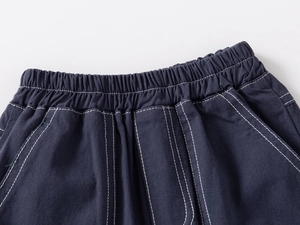 Detail of dark blue boys shorts featuring elastic waistband and white contrast stitching