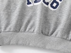 Detail of grey knitted sweatshirt with 1926 print and ribbed hem for kids