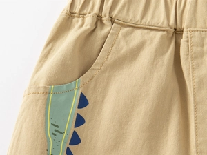 Détail macro du short en coton kaki pour garçon avec taille élastique et imprimé dinosaure