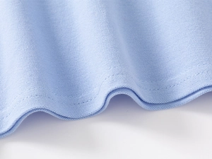 Detailed macro view of light blue pique cotton fabric texture and hem stitching on boy's T-shirt