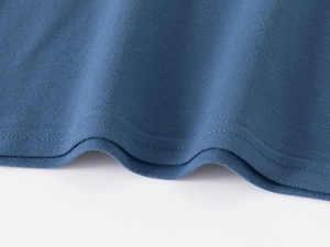 Détail du tissu piqué bleu marine et des coutures doubles sur le bas d'un polo pour garçon