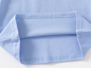 Macro view of light blue polo shirt hem with double-needle stitching and pique fabric