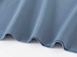 Macro shot of fog blue kids polo shirt fabric texture with durable double-stitch hem