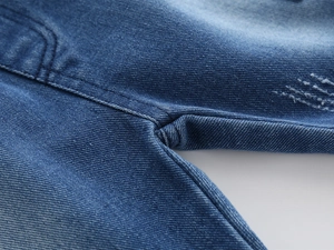 Detail view of blue denim shorts showing reinforced double stitching and distressed texture