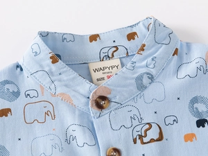Close-up of light blue baby shirt with cartoon elephant print and wooden buttons