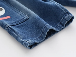 Detail of kids denim shorts featuring a cartoon eye patch and double-stitched hem finish