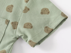 Close-up of green cotton fabric showing detailed twill texture and cute bear pattern
