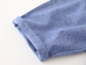 Detail of blue cotton-linen boys shorts showing cuff rolling and white stitching craft