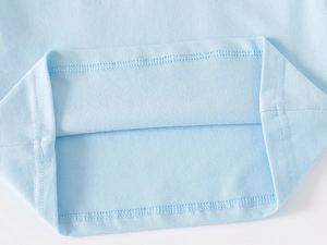 Detailed close-up of light blue cotton polo shirt hem with precise double-needle stitching