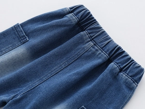 Detail of elastic waistband and stitching on boys' dark blue denim shorts with wash effect
